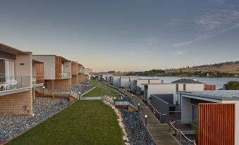 a row of modern houses on the waterfront , with a grassy area and a stone walkway leading to them at Rosevears Riverview Hotel