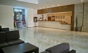 a modern hotel lobby with marble flooring , gray couches , and a reception desk with a sign on it at Hotel Bulgaria