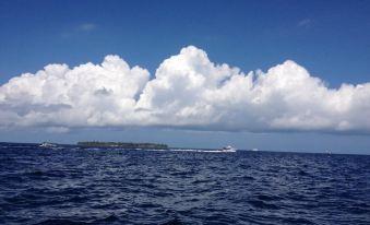 a boat is sailing on a body of water with clouds in the sky and islands in the distance at Paradise Lagoon