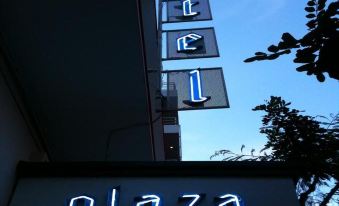 "a neon sign above a building that reads "" plaza "" with the letter "" l "" in blue letters" at Plaza Hotel