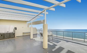 a rooftop patio with a view of the ocean , featuring a dining table and chairs at Mantra Mooloolaba Beach