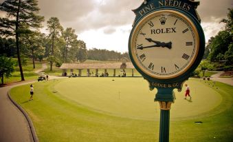 a golf course with a rolex clock on the wall , indicating the time as 2 0 1 3 british open golf championship at Pine Needles Lodge & Golf Club