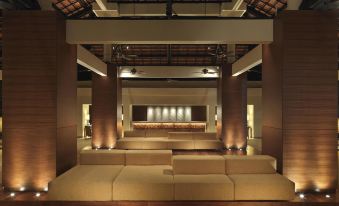 a large , modern room with high ceilings and stone pillars , containing several couches arranged in rows at Hyatt Regency Kuantan Resort