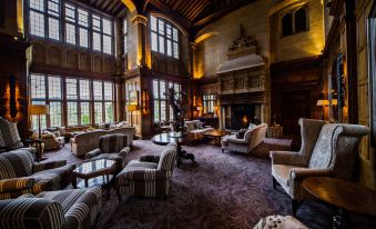 a spacious living room with high ceilings , large windows , and a fireplace , filled with comfortable furniture and a cozy atmosphere at Bovey Castle