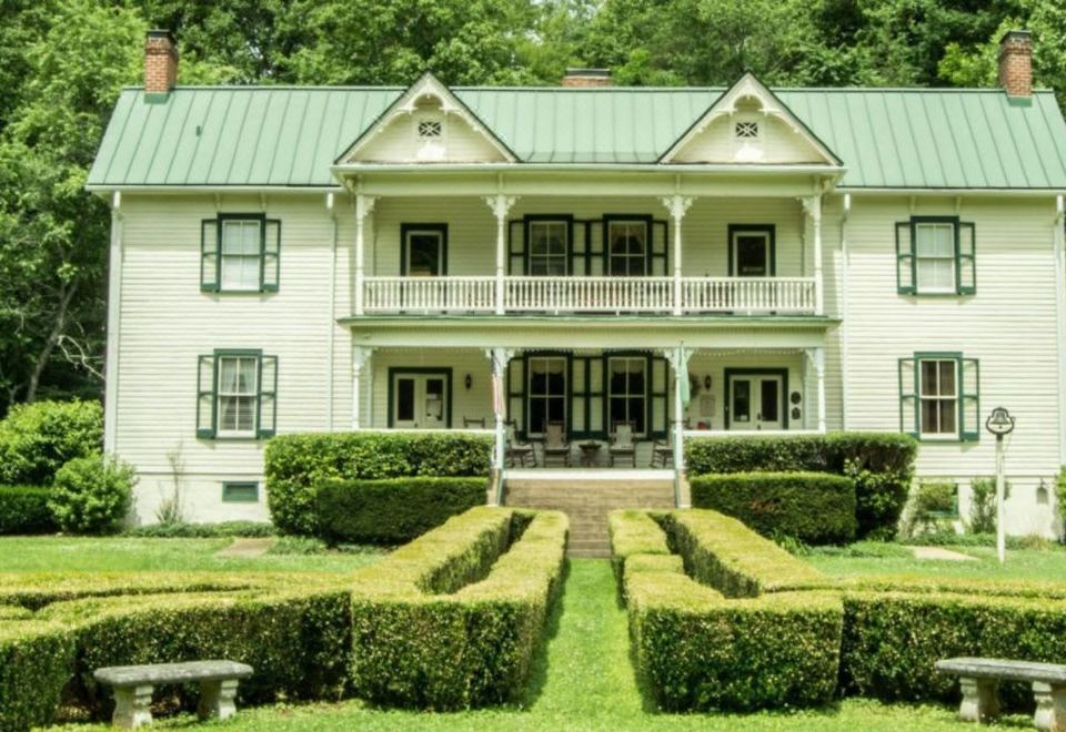 a large white house with a green roof and two balconies is surrounded by a well - maintained garden at The Mountain Rose Inn