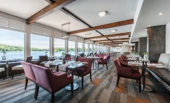 a large dining room with multiple tables and chairs , as well as a view of a lake outside at Estérel Resort