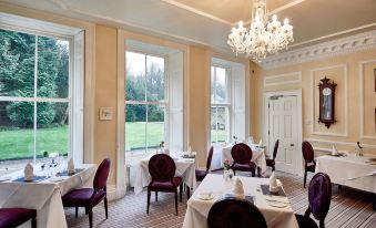 a dining room with a large chandelier hanging from the ceiling , creating a warm and inviting atmosphere at Eshott Hall