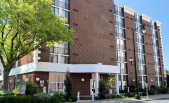 a brick apartment building on a street corner , with trees and bushes in the foreground at Best Western Plus Wilkes Barre Center City