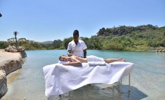 a man is giving a woman a massage on a massage table near a body of water at Amalinda Lodge