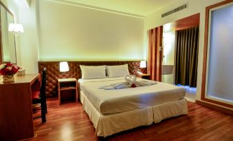 a large bed with a wooden headboard and white linens is in a room with hardwood floors at Viva Hotel Songkhla
