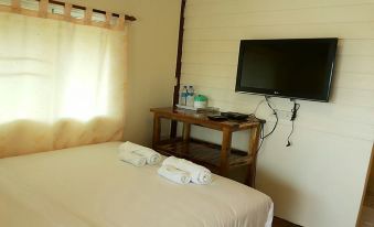a cozy bedroom with a bed , towels , and a flat screen tv on a wooden table at Sampaongern Home Stay