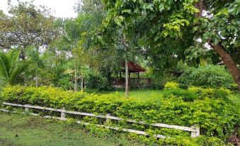 a wooden gazebo surrounded by lush green trees and a white fence , providing a serene atmosphere at Rainbow Resort