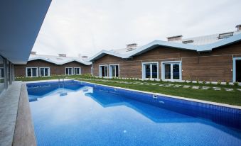 a large swimming pool is surrounded by a building with blue water and white roof tiles at La Vida Hotel