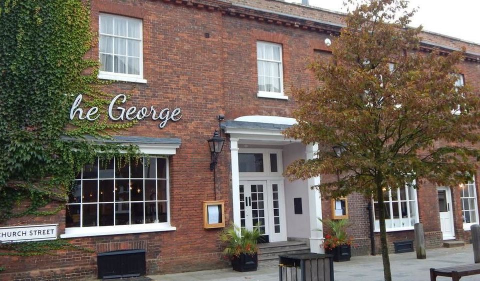 "a brick building with the name "" george "" on it , located in a town square near a street" at The George at Baldock