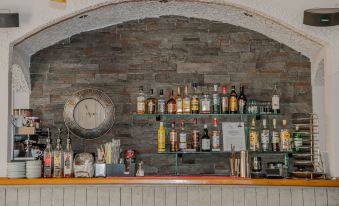 a bar with various bottles and glasses , including some on shelves and one in the corner at Plaza Hotel