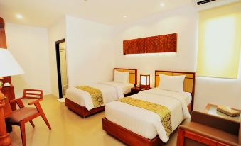 a hotel room with two beds , a wooden headboard , and white bedding , along with some other furnishings at Kautaman Hotel