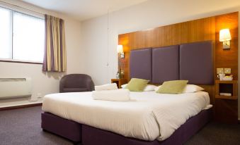a large bed with a purple headboard and white linens is in a hotel room at Hello Hotel