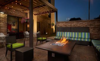 a patio with a fire pit surrounded by couches , chairs , and tables , creating a cozy atmosphere at Home 2 Suites by Hilton Muskogee