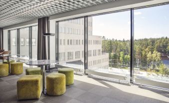 a modern office space with large windows , green velvet chairs , and a glass table in front of the window at Quality Hotel Winn Haninge