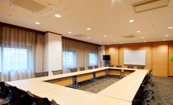 a large conference room with a long table , chairs , and a projector screen on the wall at Daiwa Roynet Hotel Hachinohe