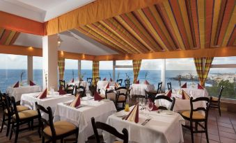 an elegant dining room with a view of the ocean , filled with tables and chairs set up for a meal at Precise Resort Tenerife