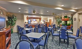 a restaurant with multiple tables and chairs , a bar area , and potted plants on the wall at Holiday Inn Express Mackinaw City