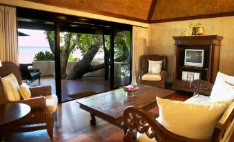 a living room with a wooden floor and white furniture , including a couch , chairs , and a coffee table at Small Luxury Hotels of the World - Pacific Resort Aitutaki