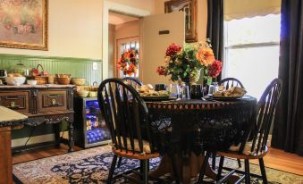 a dining room with a round table surrounded by chairs , and a refrigerator in the background at Taylor Edes Inn