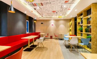 a modern and colorful office space with a red couch , white tables , and wooden floors at Ibis Hotel (Harbin Museum Subway Station)