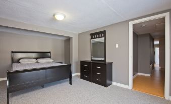 a modern bedroom with a black bed , dresser , and mirror , as well as a carpeted floor at White House Farm