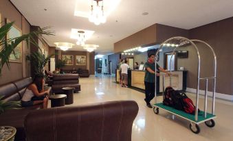 a hotel lobby with a man pushing a luggage cart and two people standing nearby at Eurotel Angeles