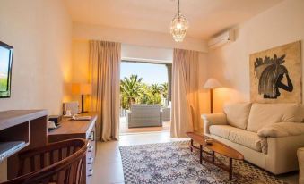 a living room with a couch , chair , and television is shown with an open door leading to an outdoor patio at Hotel Simius Playa