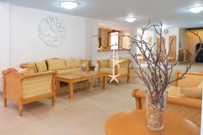 a well - lit living room with wooden furniture , including a couch , chairs , and a dining table at Hotel Summery