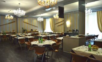 a large dining room with multiple tables and chairs arranged for a group of people to enjoy a meal together at Garda Hotel