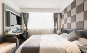The bedroom features a double bed, a desk, and a chair positioned in front of a large window that offers a view of the rest area at Zhotels (Shanghai West Nanjing Road Westgate Mall)