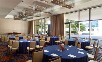 a well - lit conference room with round tables and chairs , set for a meeting or event at Omni Frisco-Dallas Hotel at the Star