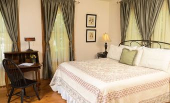 a large bedroom with a wooden floor , white beddings , and green curtains on the windows at Delta Street Inn