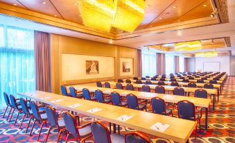 a large conference room with rows of chairs arranged in a semicircle , and a podium at the front of the room at Leonardo Hotel Karlsruhe