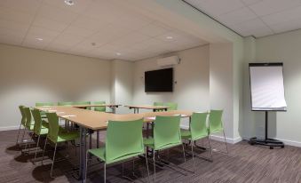 a conference room with a table and chairs , a television on the wall , and light - colored walls at Best Western Plus Hotel Amstelveen