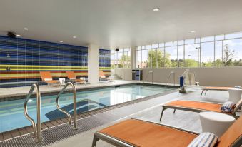 an indoor swimming pool with a hot tub , surrounded by lounge chairs and a dining area at Aloft Hillsboro-Beaverton