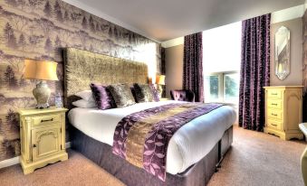 a large bed with purple and white bedding is in a room with a window at Seacrest Hotel