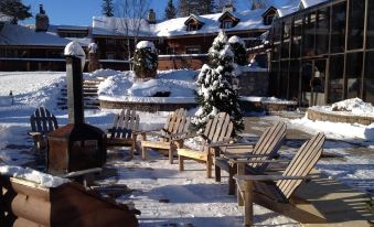 a snowy scene with a group of adirondack chairs placed on a patio , surrounded by snow - covered ground at Hotel & Spa Mont Gabriel