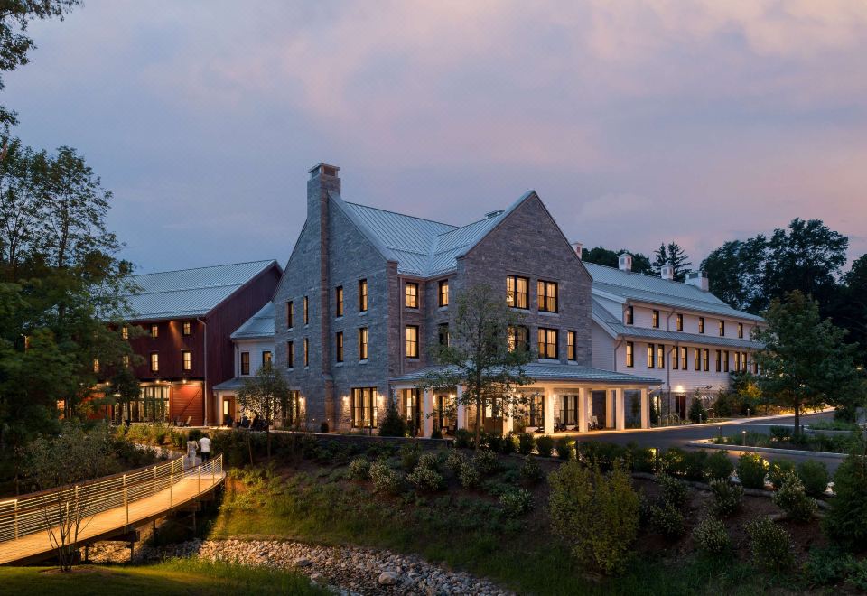 a large stone building with a pointed roof , surrounded by trees and situated near a body of water at The Williams Inn