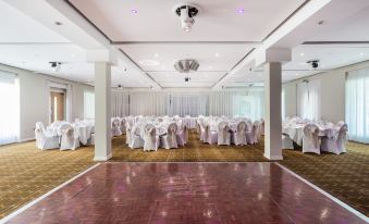 a large , empty banquet hall with white tablecloths and chairs set up for a formal event at Holiday Inn Sittingbourne