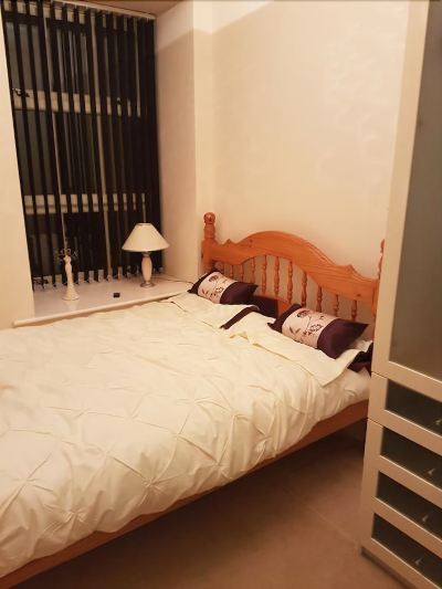 a bedroom with a wooden bed and white bedding , along with a window and lamp at Knights