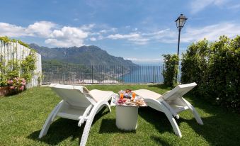 a white outdoor table and chairs set up on a grassy lawn overlooking a body of water at Villa Piedimonte