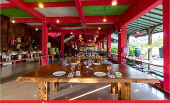 a large dining area with red and green walls , wooden tables , and chairs , as well as various food items on display at Coconut Island Carita