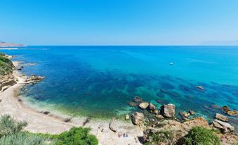 a beautiful beach scene with clear blue water , white sand , and people enjoying the sunny day at Hotel Punta Nord Est