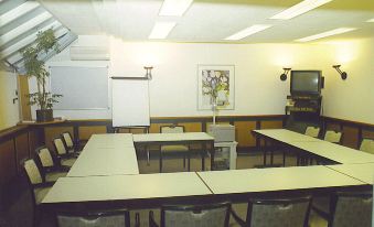 a conference room with several tables and chairs , a whiteboard , and a painting on the wall at Avenue Hotel