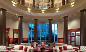 a luxurious hotel lobby with red and white furniture , a chandelier , and large windows offering views of the city at Omni Providence Hotel